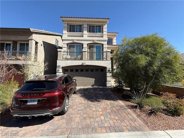 mediterranean / spanish-style house with a garage, decorative driveway, and stucco siding