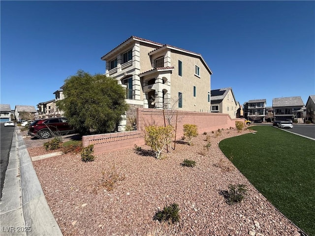 view of home's exterior with a yard, fence, a tiled roof, and stucco siding