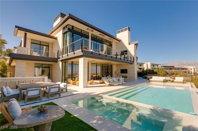 back of house featuring a patio area, an outdoor hangout area, a balcony, and a pool with hot tub