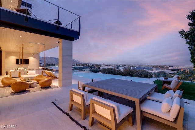 patio terrace at dusk with outdoor lounge area and a balcony