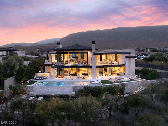 back house at dusk featuring a mountain view, a balcony, and a jacuzzi