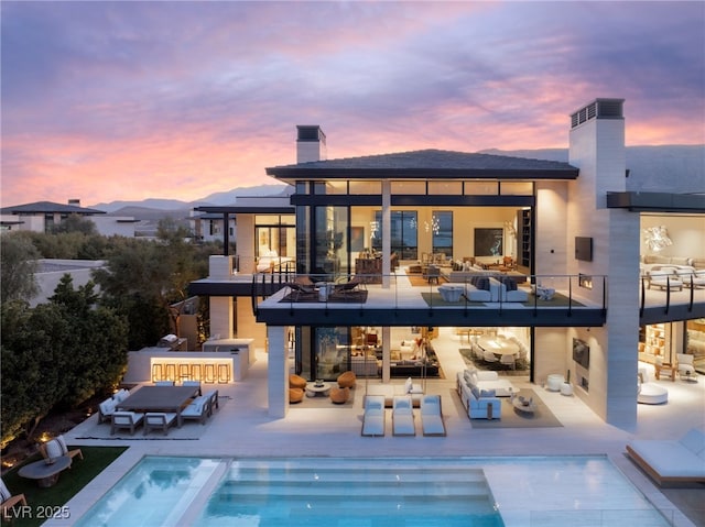 back house at dusk featuring an outdoor living space and a swimming pool with hot tub