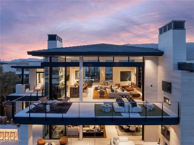 back house at dusk with an outdoor living space