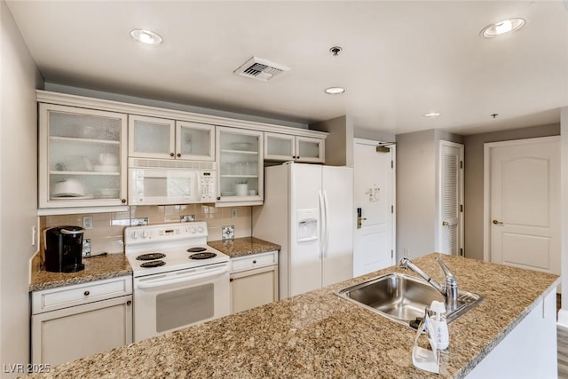 kitchen with sink, white appliances, light stone countertops, and decorative backsplash