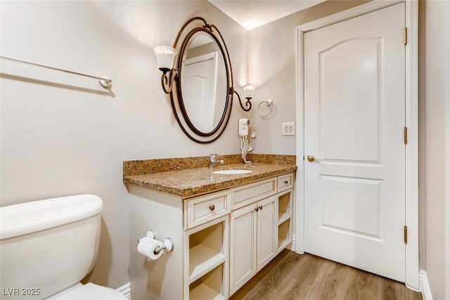 bathroom with toilet, hardwood / wood-style flooring, and vanity