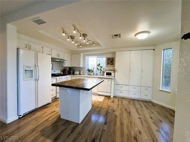 kitchen with white appliances, white cabinetry, a kitchen island, a textured ceiling, and light hardwood / wood-style floors