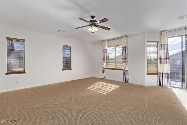 carpeted empty room with ceiling fan and a wealth of natural light