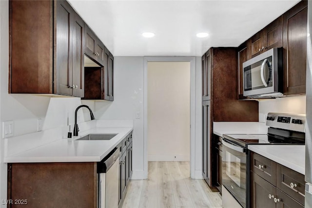 kitchen with dark brown cabinets, light hardwood / wood-style flooring, sink, and stainless steel appliances