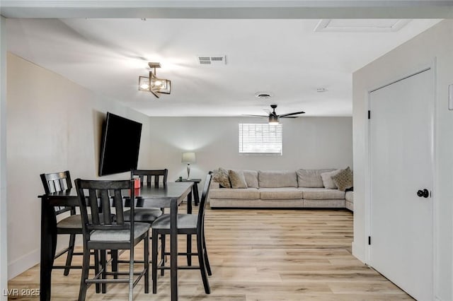 dining area featuring light hardwood / wood-style floors and ceiling fan with notable chandelier