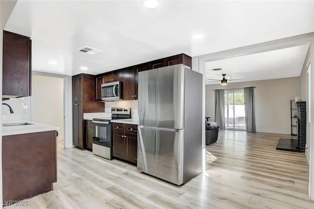 kitchen with ceiling fan, light wood-type flooring, stainless steel appliances, and sink