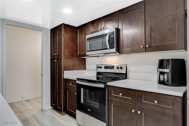 kitchen with dark brown cabinets, stainless steel appliances, and light hardwood / wood-style flooring