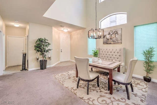 carpeted dining area with a healthy amount of sunlight, a chandelier, and a high ceiling