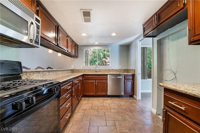 kitchen with stainless steel appliances, light stone counters, and sink