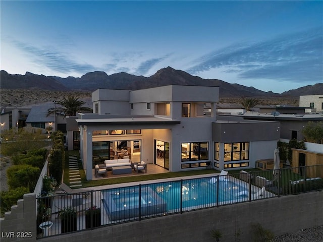 back of property with outdoor lounge area, a fenced in pool, a patio area, and a mountain view