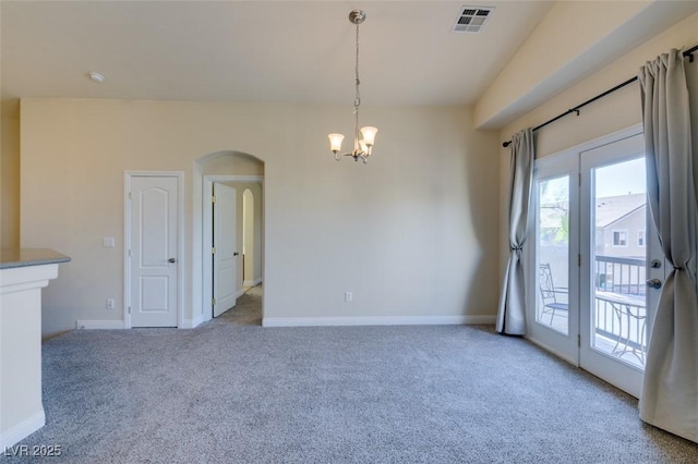 carpeted empty room with a notable chandelier