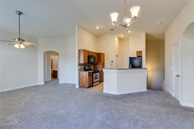 kitchen featuring refrigerator, decorative light fixtures, ceiling fan with notable chandelier, stainless steel gas stove, and light carpet