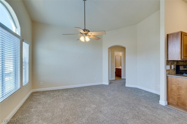 unfurnished living room featuring ceiling fan, light colored carpet, and a healthy amount of sunlight