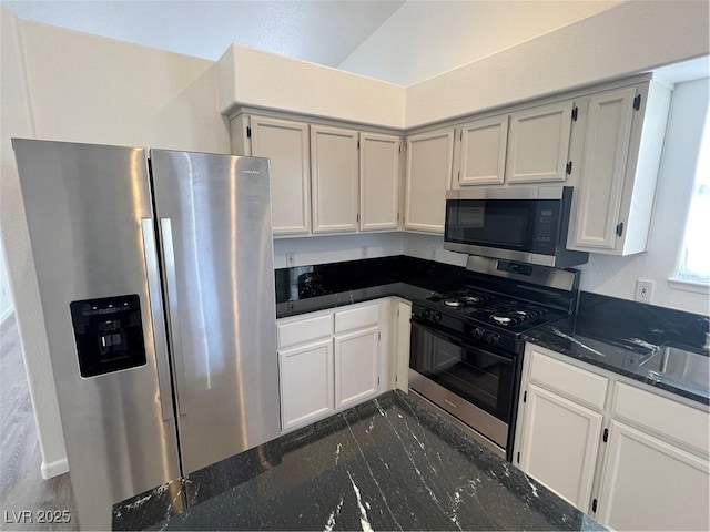 kitchen featuring stainless steel appliances, dark stone countertops, and white cabinets