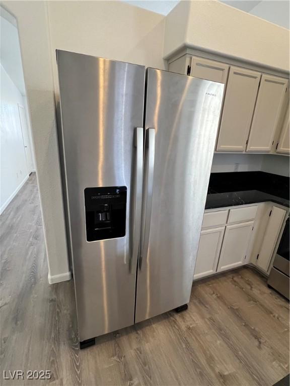 kitchen with dark countertops, white cabinetry, stainless steel appliances, and wood finished floors