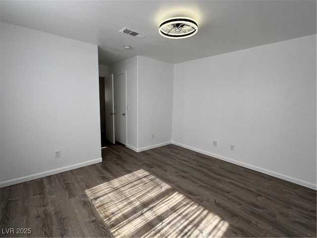 unfurnished room featuring visible vents, baseboards, and dark wood-type flooring