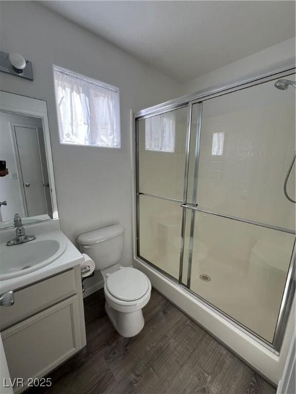 full bathroom featuring wood finished floors, vanity, toilet, and an enclosed shower