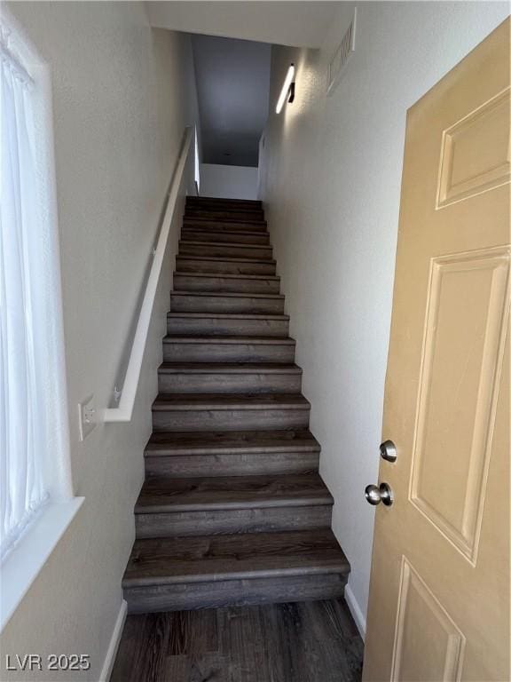 stairs featuring wood finished floors, visible vents, and baseboards