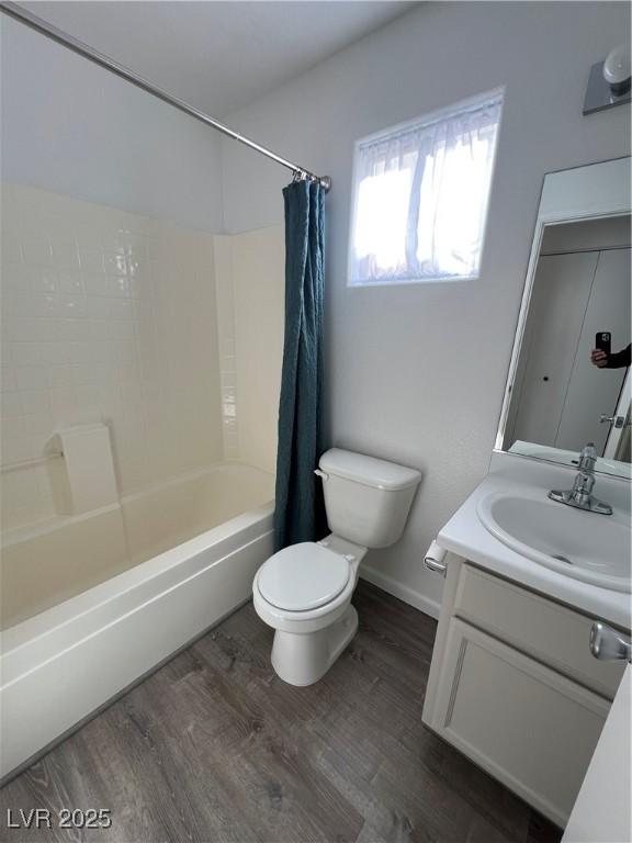 bathroom featuring toilet, wood finished floors, vanity, baseboards, and shower / bath combo with shower curtain