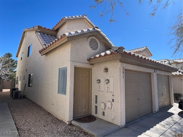 view of front of property featuring a garage, a tile roof, and stucco siding