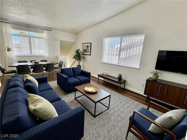 living room featuring vaulted ceiling, baseboards, and wood finished floors