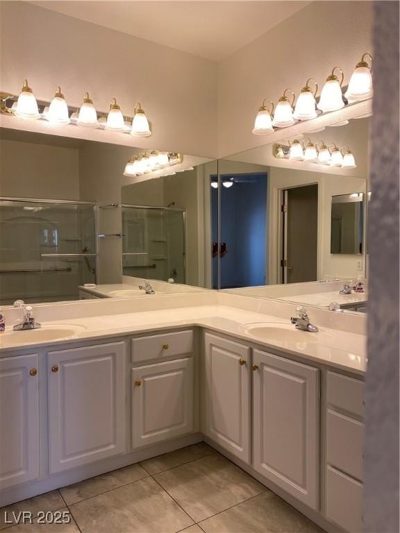 full bath with double vanity, a shower stall, a sink, and tile patterned floors