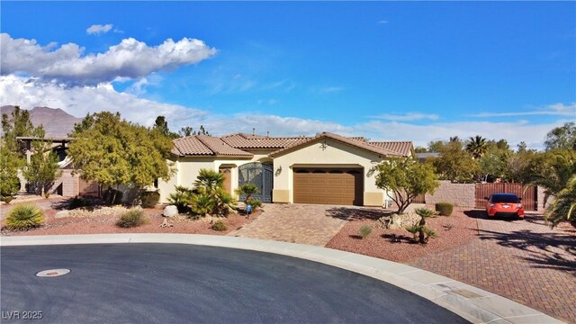 mediterranean / spanish house with driveway, a tile roof, stucco siding, an attached garage, and fence