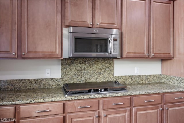 kitchen featuring light stone countertops, stainless steel appliances, and decorative backsplash