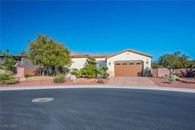 mediterranean / spanish home featuring fence, driveway, stucco siding, a garage, and a tile roof