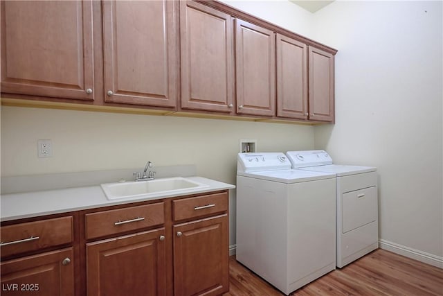 laundry room with independent washer and dryer, baseboards, a sink, light wood-style flooring, and cabinet space
