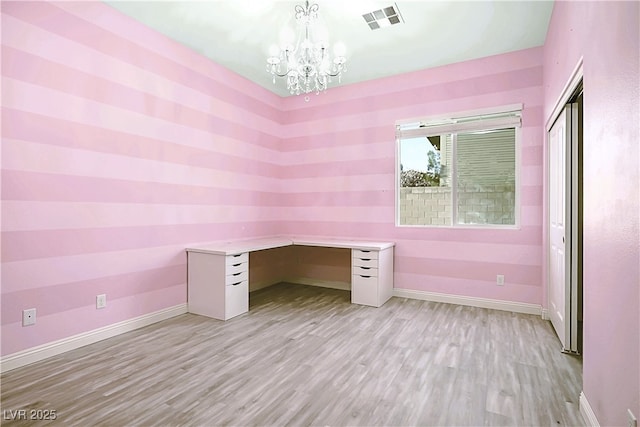 unfurnished office featuring visible vents, baseboards, light wood-type flooring, built in study area, and an inviting chandelier