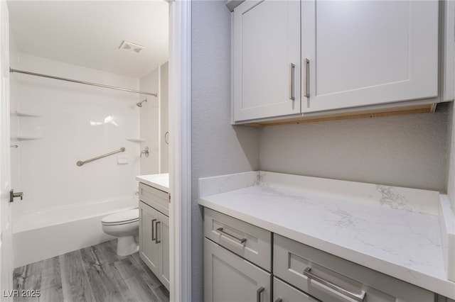 full bathroom with toilet, wood-type flooring, vanity, and washtub / shower combination