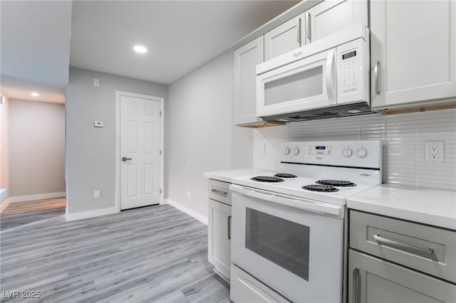 kitchen with white appliances, light hardwood / wood-style floors, white cabinetry, and tasteful backsplash