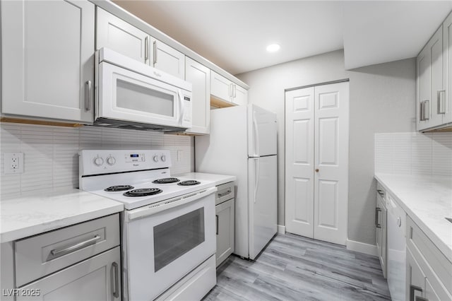 kitchen featuring white appliances, light wood-type flooring, light stone counters, and tasteful backsplash