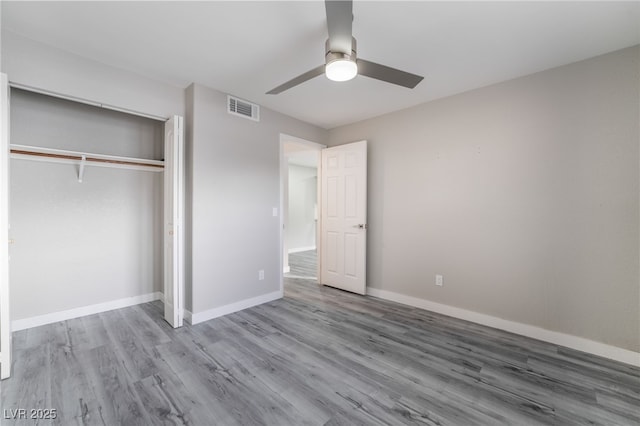 unfurnished bedroom with ceiling fan, wood-type flooring, and a closet