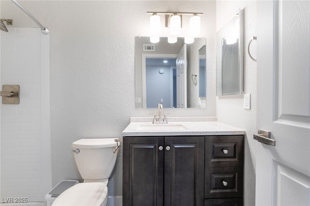 bathroom featuring vanity, toilet, and walk in shower