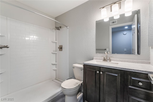 bathroom featuring a shower, vanity, and toilet