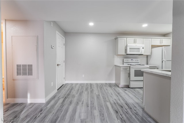 kitchen with white cabinetry, white appliances, and light hardwood / wood-style flooring