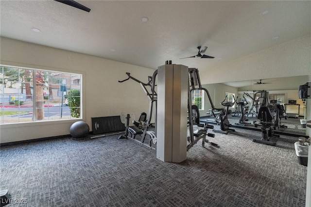 exercise room featuring ceiling fan, vaulted ceiling, and carpet