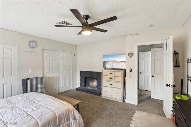 carpeted bedroom with a fireplace, a closet, a textured ceiling, and ceiling fan