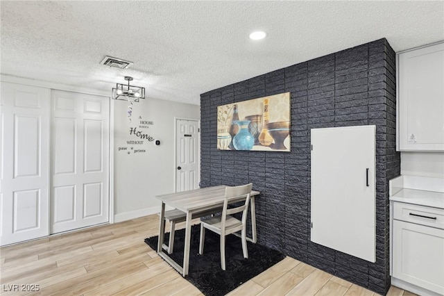 dining space featuring light hardwood / wood-style floors and a textured ceiling