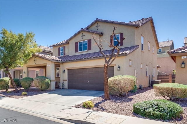 mediterranean / spanish-style house featuring concrete driveway, an attached garage, a tile roof, and stucco siding