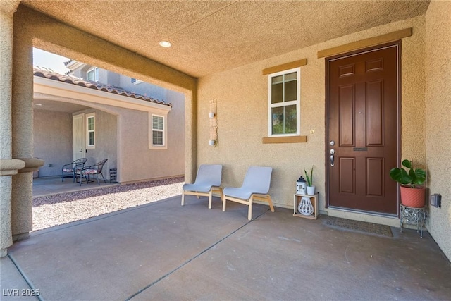 entrance to property with stucco siding, a tile roof, and a patio area