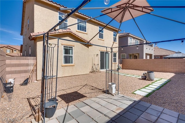 rear view of house with stucco siding, a residential view, a fenced backyard, and a tiled roof