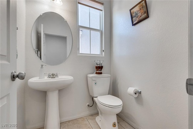 half bathroom with tile patterned floors, toilet, baseboards, and a sink