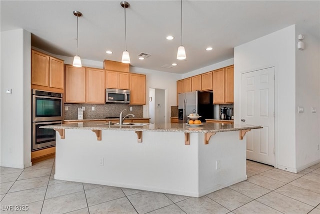 kitchen with visible vents, a sink, stainless steel appliances, light tile patterned floors, and decorative backsplash